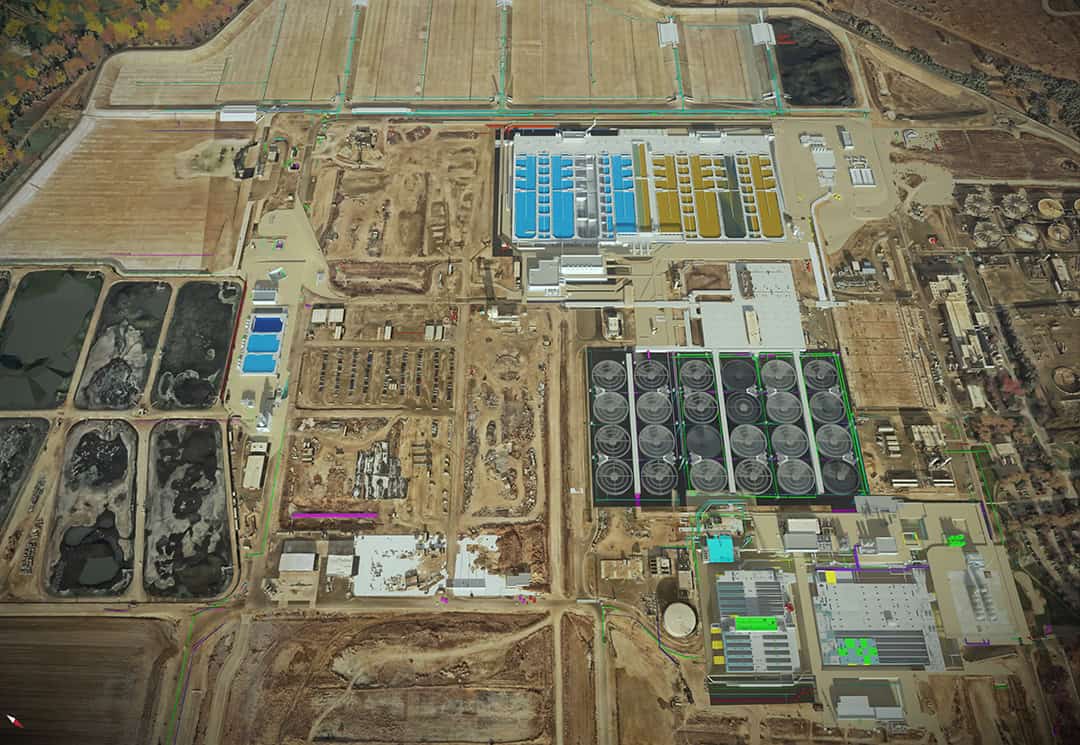 Aerial view of an industrial facility showcasing large storage tanks, buildings, rectangular ponds, pipelines, and surrounding construction areas&mdash;ideal for optimizing site design or creating accurate digital twins.