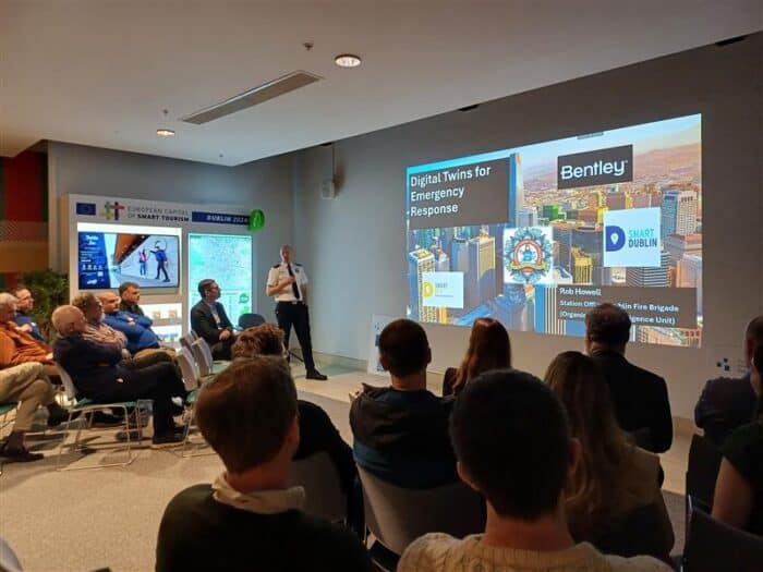People seated in a room watching a presentation on Digital Twins for Emergency Response with a slide featuring Bentley and Smart Dublin logos.