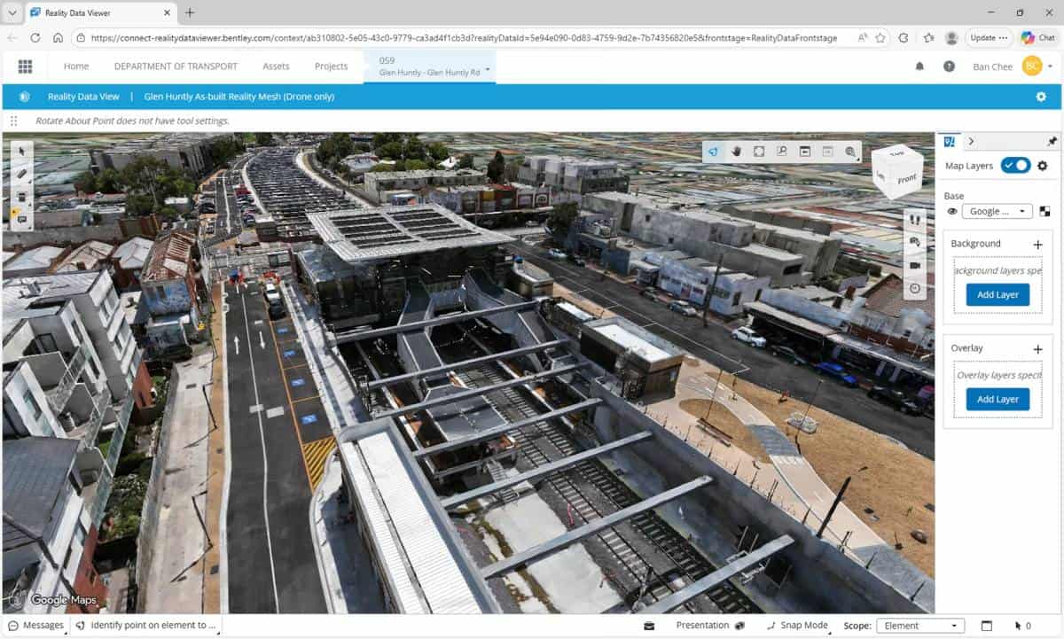 Aerial view of a railway station under construction, surrounded by roads, vehicles, and residential buildings, enriched with transport reality data in a digital project management interface.