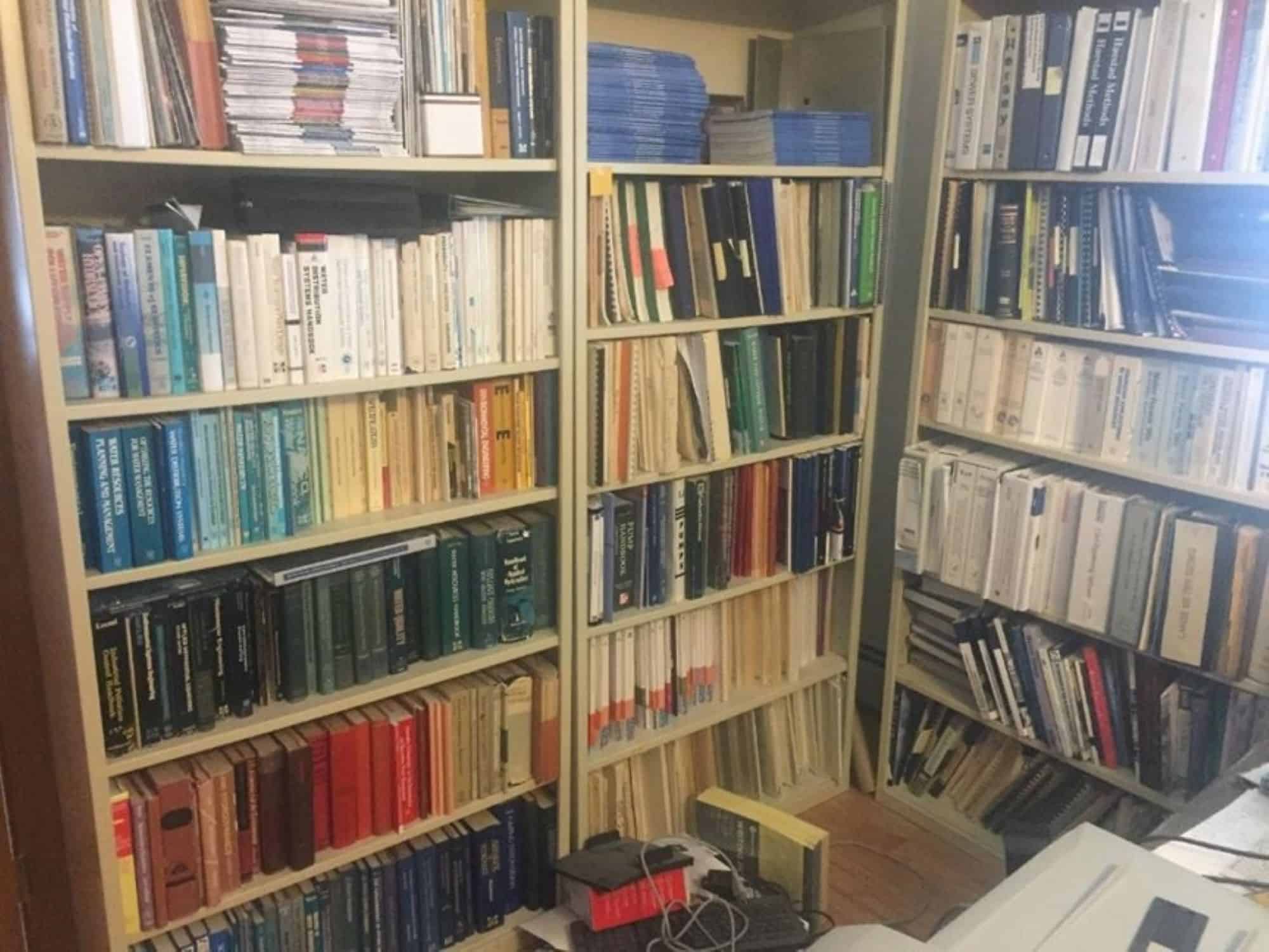 A cluttered bookshelf filled with books of various sizes.