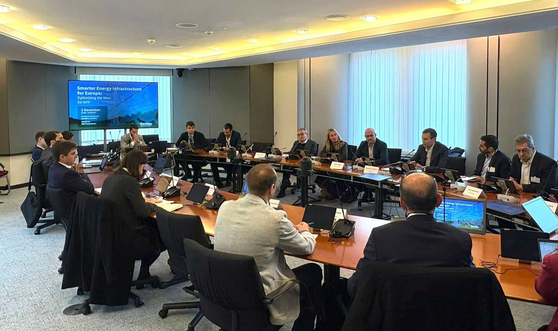 A group of professionals seated around a conference table attend a presentation on Smarter Energy Infrastructure for Europe.