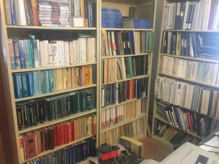 A well-organized room showcasing numerous books on shelves alongside a computer, ideal for learning and research.