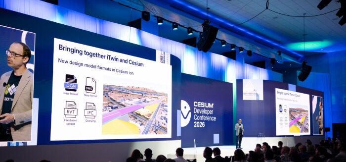A speaker presents slides about design model formats at the Cesium Developer Conference 2026, with an audience seated in a modern, well-lit conference hall.