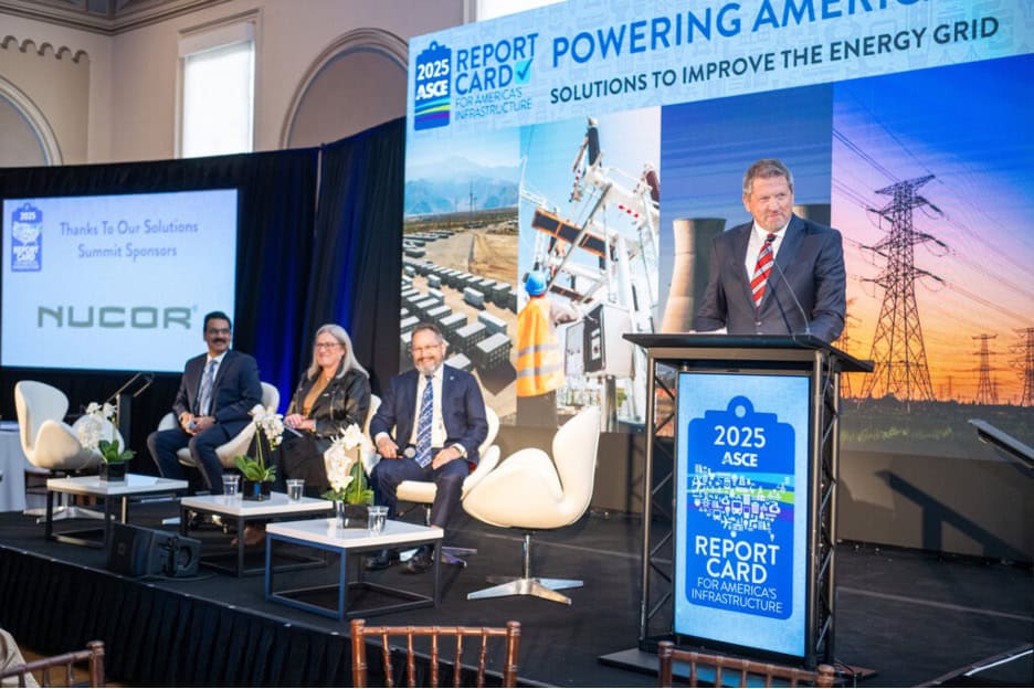 A man speaks at a podium during the 2025 ASCE Report Card event, with three panelists seated on stage and energy infrastructure images displayed in the background.
