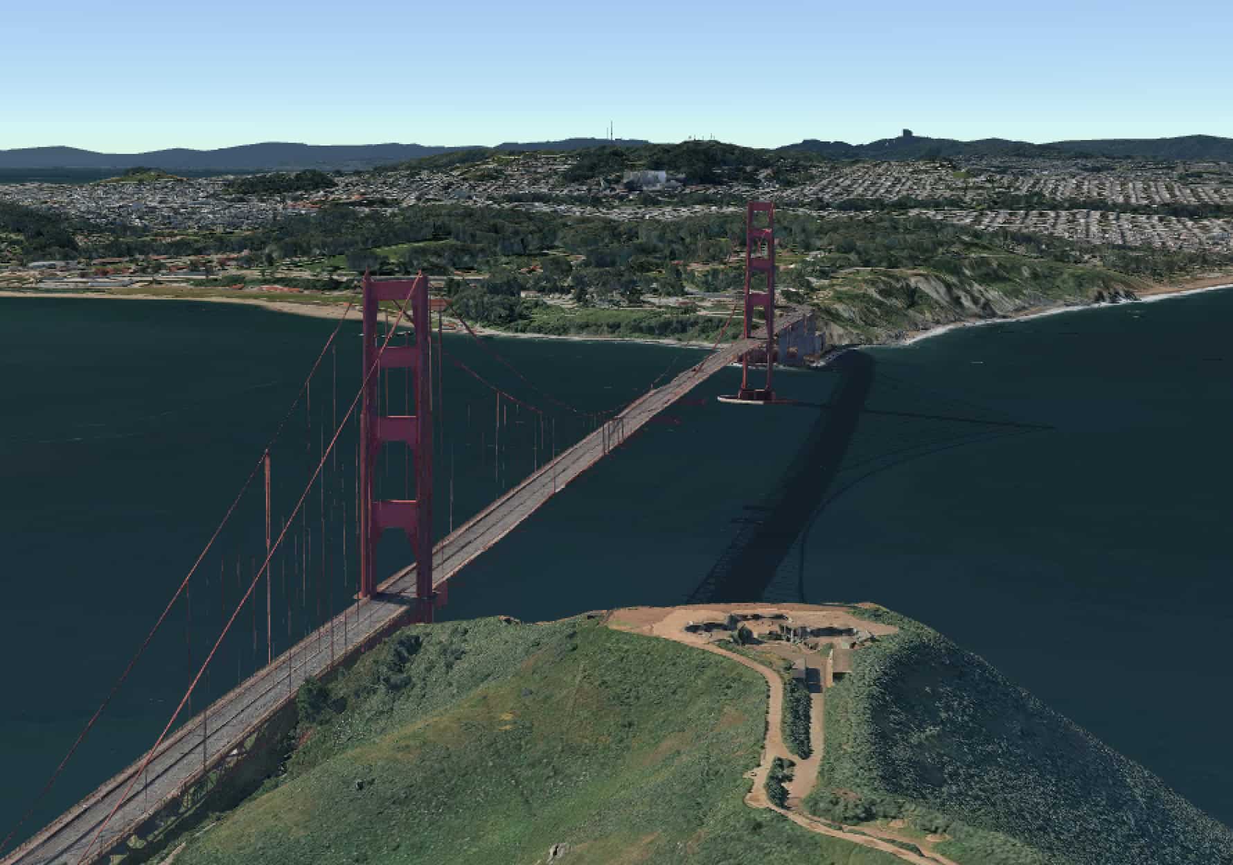 Aerial view of the Golden Gate Bridge, one of America at 250&rsquo;s marvels, spanning over water with green hills in the foreground and a cityscape in the background.