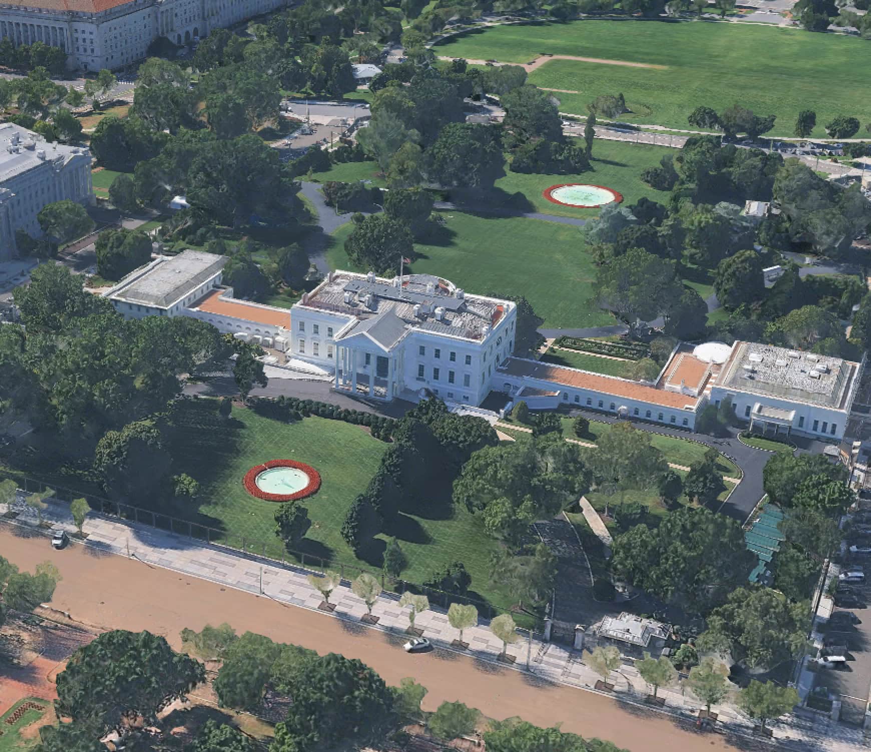 Aerial view of the White House surrounded by trees, lawns, and nearby buildings in Washington, D.C.