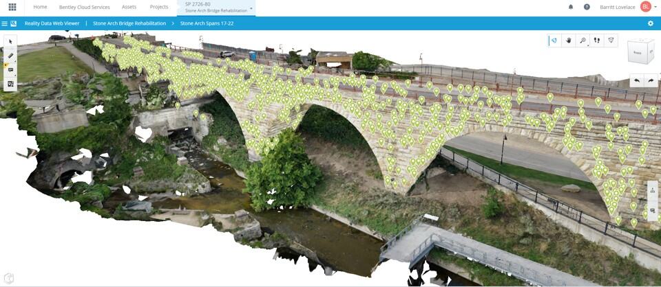 3D model of a stone arch bridge with many data points marked on its surface, spanning over a small stream and surrounded by grass and pathways.