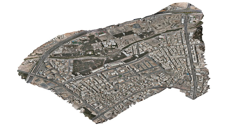 Aerial view of an urban area with dense buildings, roads, and patches of undeveloped land, captured using Unified Reality Modeling to illustrate a mix of residential and industrial zones.