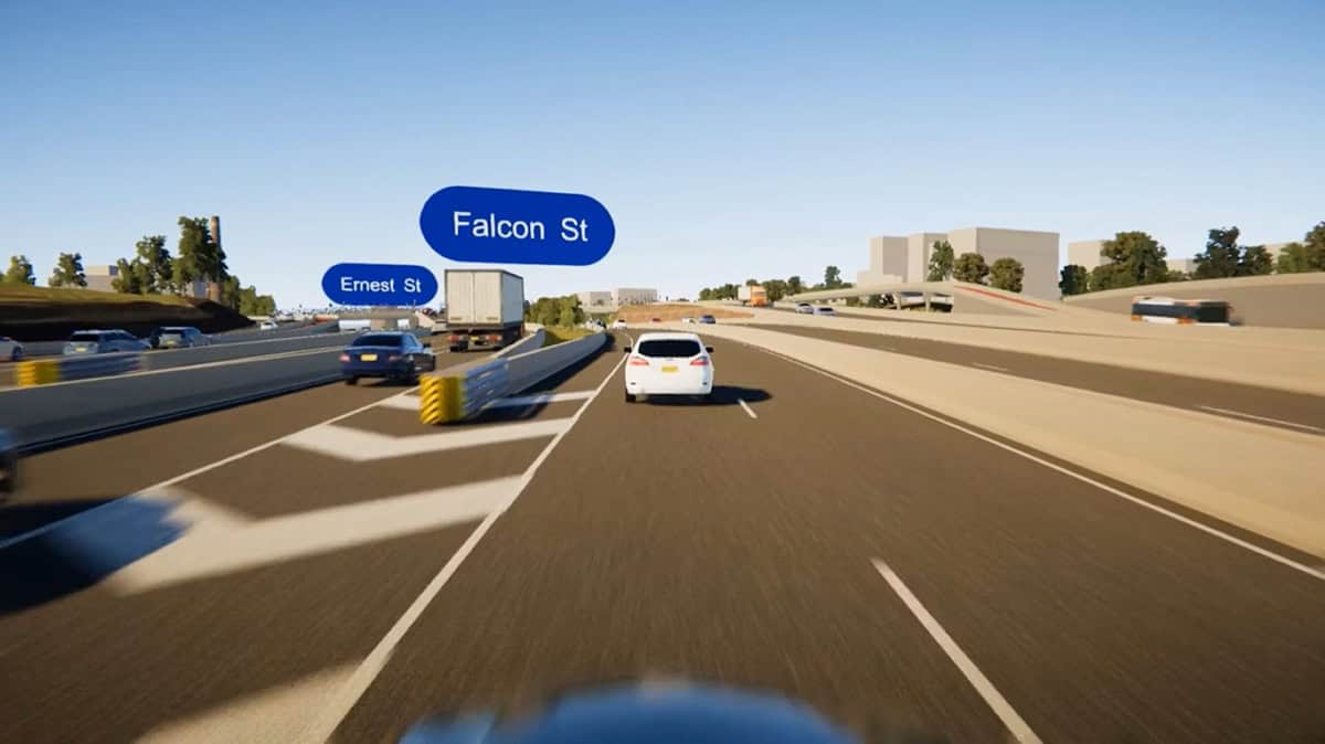 A highway scene on the Warringah Freeway shows several cars driving; blue road signs label Falcon St and Ernest St above two exits. Urban freeways and city buildings, along with trees, are visible in the background.