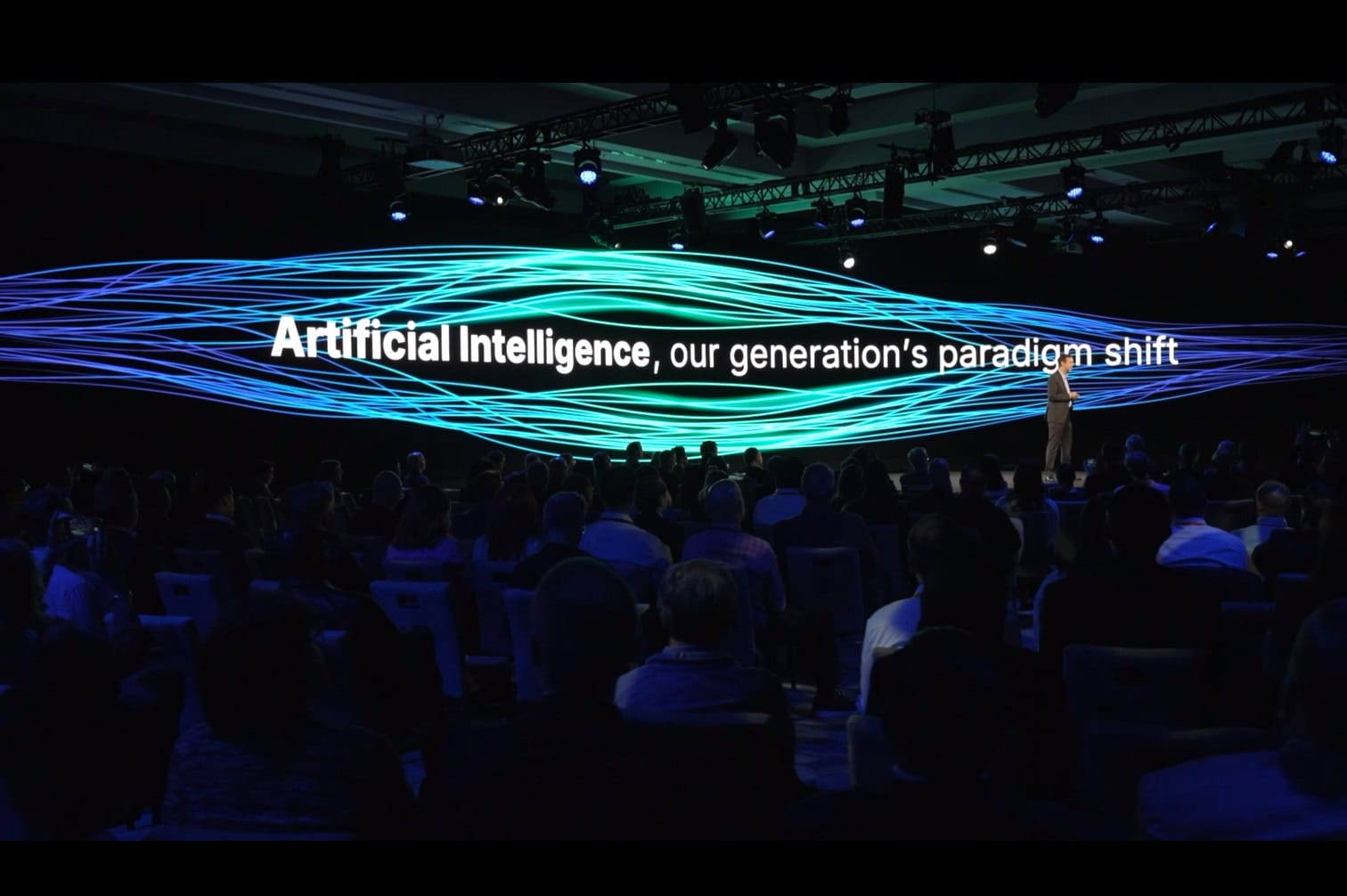 Bentley Chief Executive Officer Nicolas Cumins on stage with a large digital backdrop displaying Artificial Intelligence, our generation’s paradigm shift to an audience at a conference.