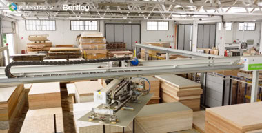In this Partner Spotlight, a robotic arm from Archway Systems moves large wooden boards in a spacious, well-lit factory with stacks of wood panels and industrial equipment visible.