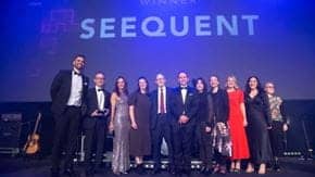 A group of people standing in front of a "SEEQUENT" sign