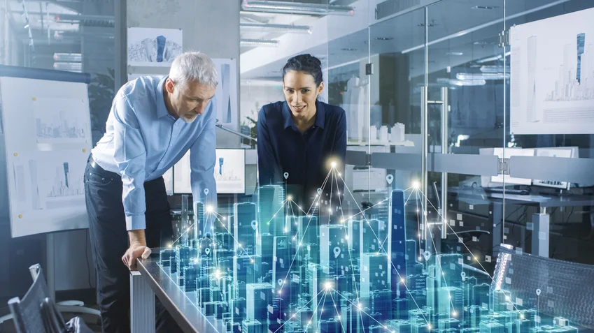 2 people looking down at a table with a digital 3D city rising out of the table