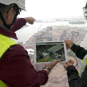 Ingenieure halten ein iPad in der Hand, während sie eine Stadt betrachten