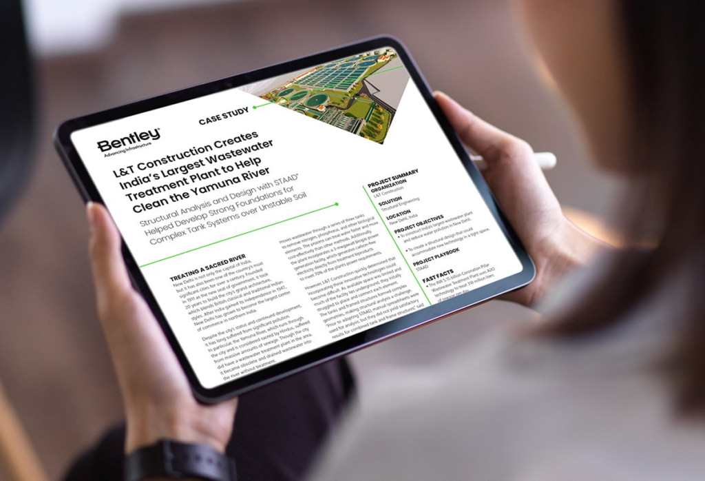 A person views an online case study on a tablet, detailing a construction project by L&T for India's largest wastewater treatment plant to help clean the Yamuna River, utilizing Structural WorkSuite for enhanced structural analysis.
