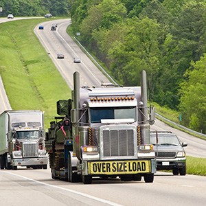 프론트 범퍼에 과대 화물을 나타내는 표지판이 있는 고속도로의 트럭