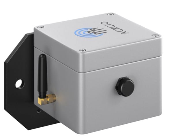 A small, gray metal electronic device with a black antenna, a black knob, and a mounting bracket, labeled “ACKO UD” with a blue signal icon on the top.