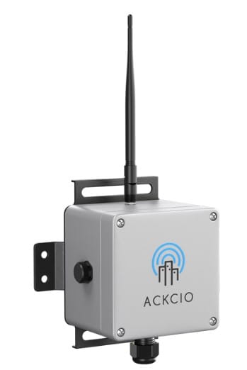 A metal device with an antenna and the ACKCIO logo on the front, mounted on a bracket, used for wireless communication or monitoring.