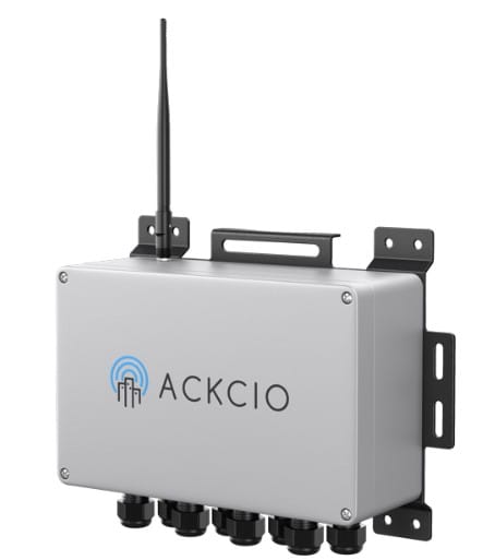 A rectangular metal device labeled "ACKCIO" with an antenna, handle, mounting brackets, and multiple cable connectors at the bottom.
