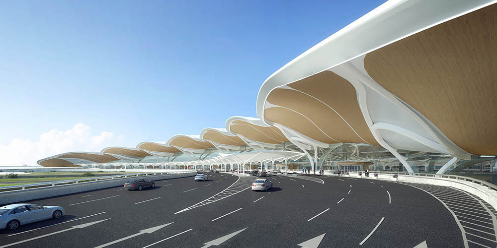A modern airport terminal features a distinctive wavy roof design, with cars driving and parked along the roadway in front under a clear blue sky.