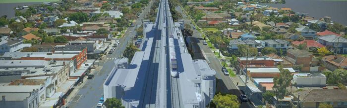An aerial view of a suburban area with a large construction project in the center, featuring a long elevated structure running through the neighborhood.