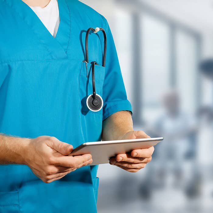 Pracownik medyczny trzymający tablet ze stetoskopem w kieszeni