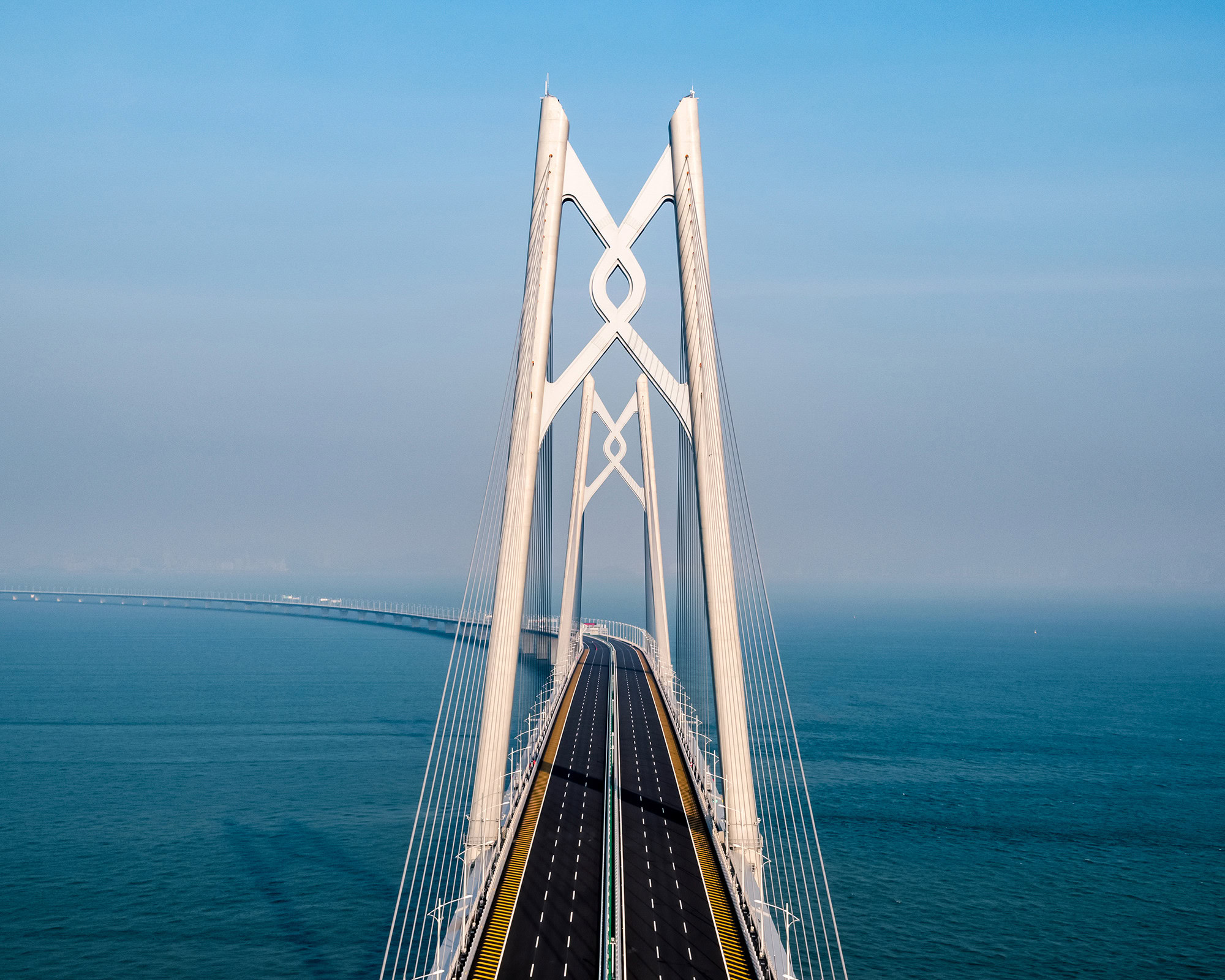 Aerial view of a resilient cable-stayed bridge extending over a body of water under a clear blue sky, showcasing the remarkable infrastructure capable of supporting modern delivery needs.