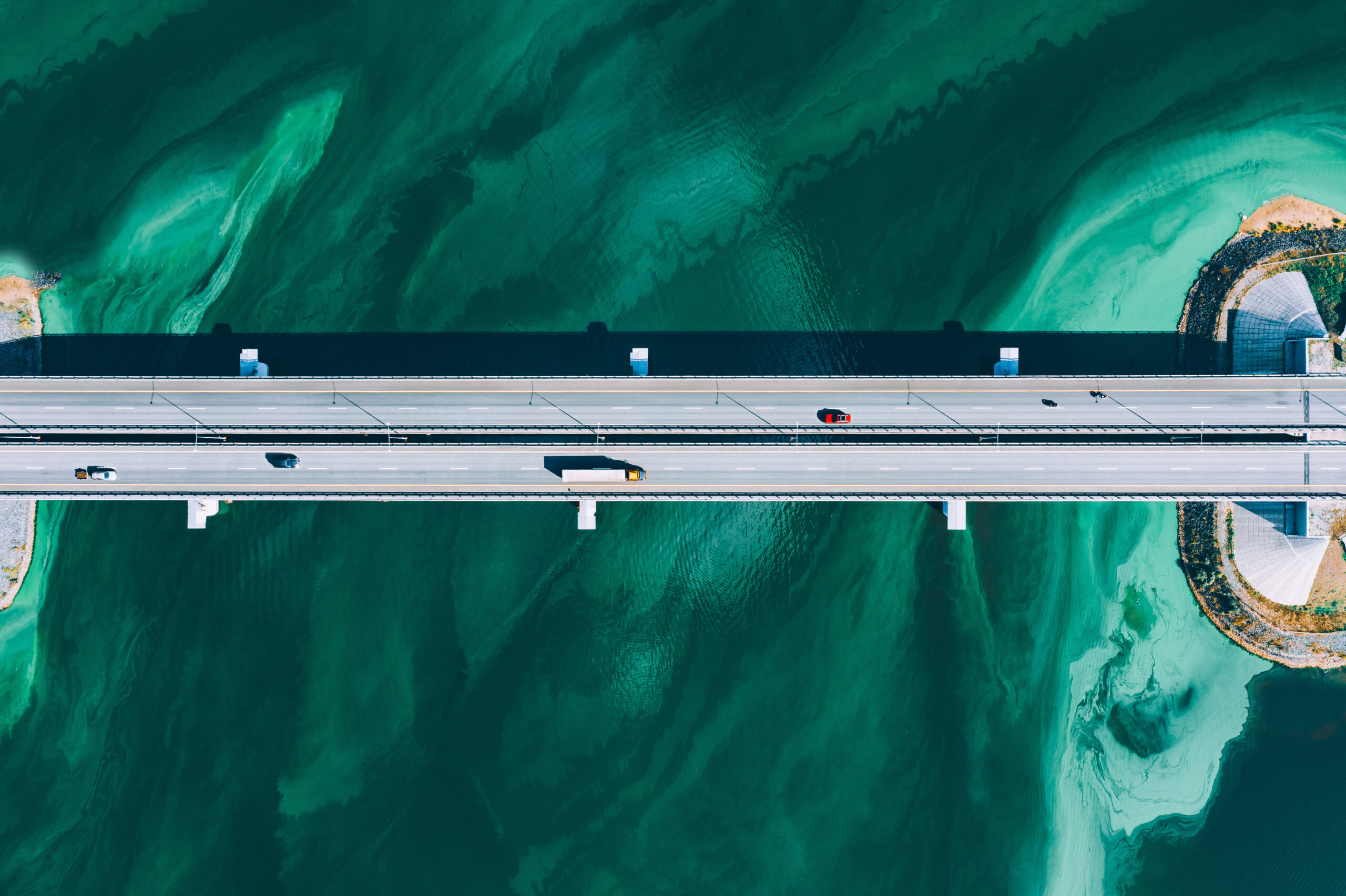 Aerial view of vehicles crossing a straight bridge over green, swirling water, designed with precision using MicroStation 2025.