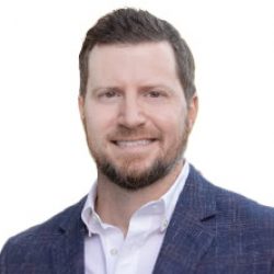 Man with short brown hair and beard wearing a blue checked blazer and white shirt, smiling at the camera against a white background, reflecting the confidence of an AI or BIM professional.