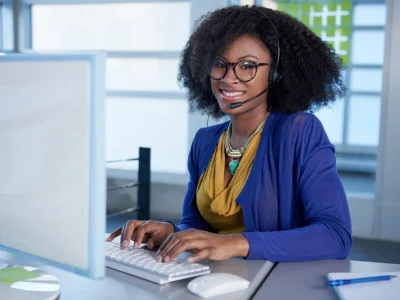 A woman wearing glasses is sitting in front of a computer using OpenFlows HAMMER software to prevent catastrophic events.