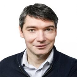 Man with short dark hair and light skin wearing a white shirt and dark sweater, smiling at the camera against a plain white background—ideal for professionals specializing in Deep Foundation Design or PLAXIS 3D analysis.