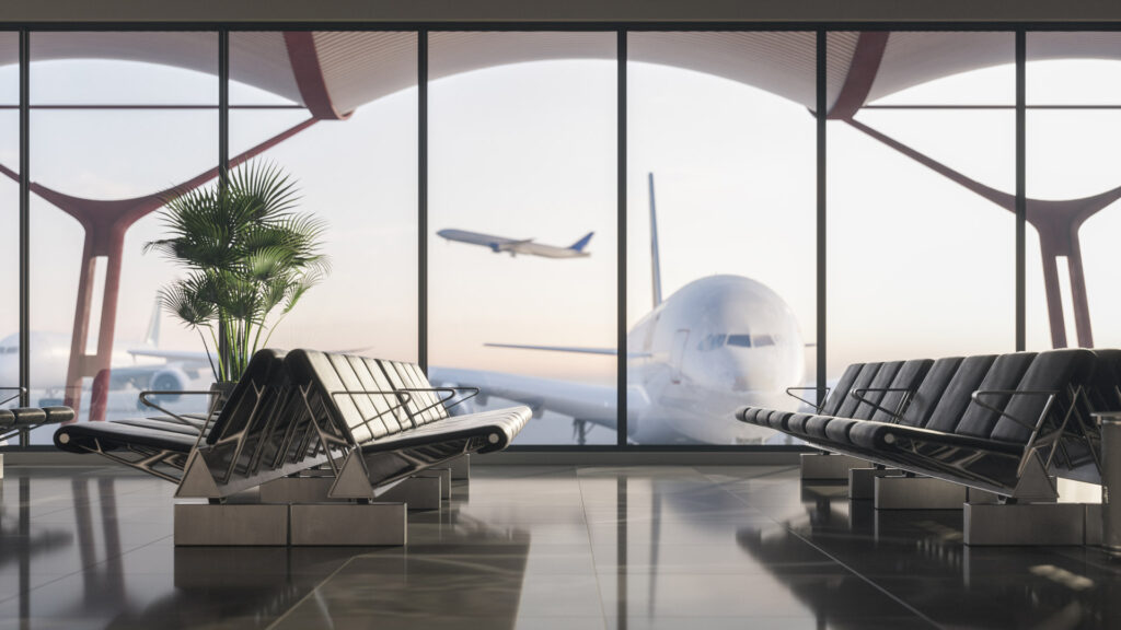 The empty airport terminal, showcasing rows of black seating and large windows revealing a stationary airplane and another taking off, highlights the new era of Indian aviation. A potted plant graces the left side.