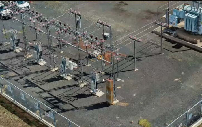 A fenced outdoor electrical substation by Essential Energy with transformers, power lines, and equipment on a gravel lot.