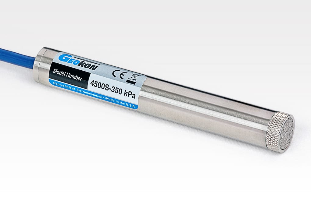 A cylindrical Geokon sensor with a labeled tag showing model number 4500S-350 kPa, connected to a blue cable, and featuring a mesh-covered end.