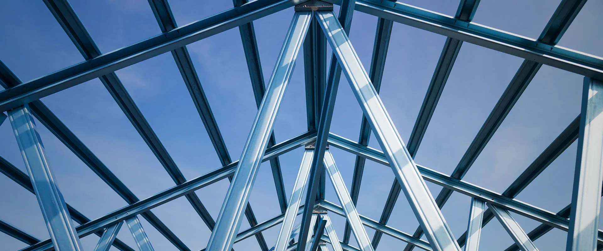Close-up view of a steel roof frame structure against a blue sky.