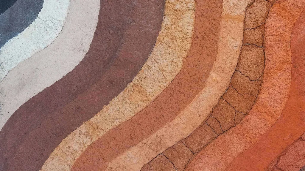 Layers of earth in shades of brown, orange, and beige form wavy, textured bands resembling geological strata—details that often appear in soil reports used by structural engineers.