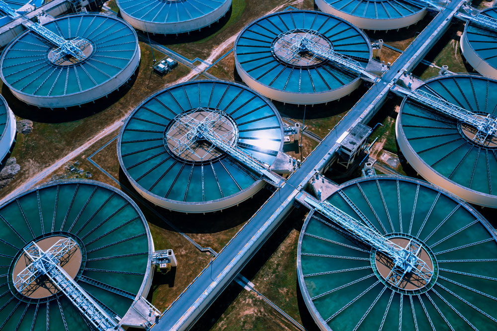Aerial view of a wastewater treatment plant with multiple circular clarifying tanks arranged in rows.