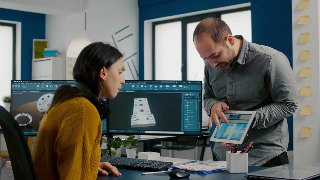 A man and woman in an office looking at a tablet.