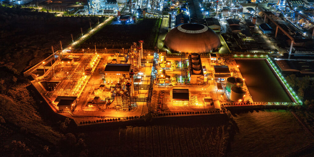 Illuminated industrial plant at night with distinctive dome-shaped structures.