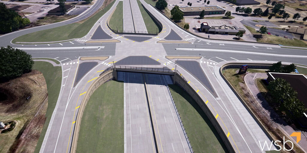 An aerial view captures the intricate dance of vehicles on a multi-lane divided highway intersection with an impressive road bridge overpass, surrounded by the lush greenery and urban development of Elk River Road.