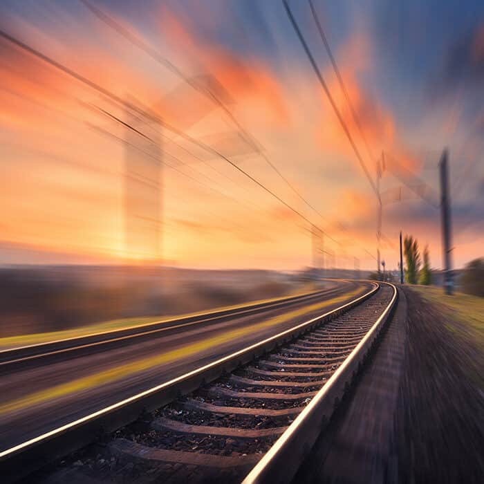 Binario ferroviario in movimento al tramonto. Stazione ferroviaria sfuocata