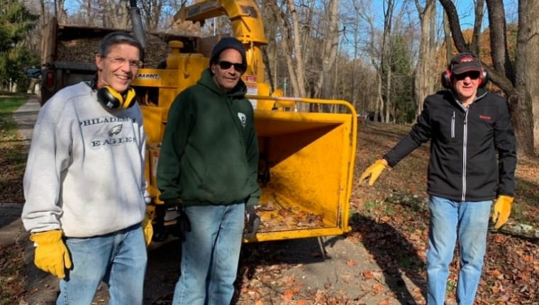 hommes debout devant une déchiqueteuse de bois