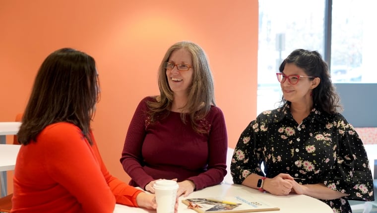 Trzy kobiety rozmawiają przy stole