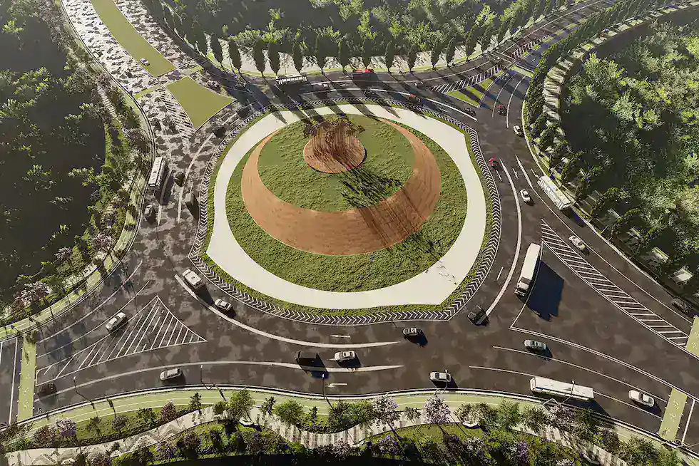 Aerial view of a large circular roundabout with vehicles traveling in multiple directions, surrounded by greenery and well-marked road lanes.