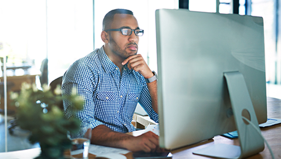 A man sitting at a desk in front of a computer, giving a demo.