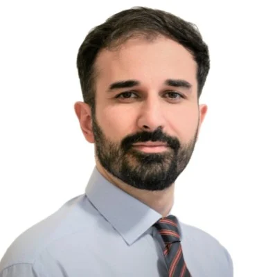 A professional portrait of a man with a beard, wearing a light blue shirt and striped tie, against a white background, presenting a webinar.