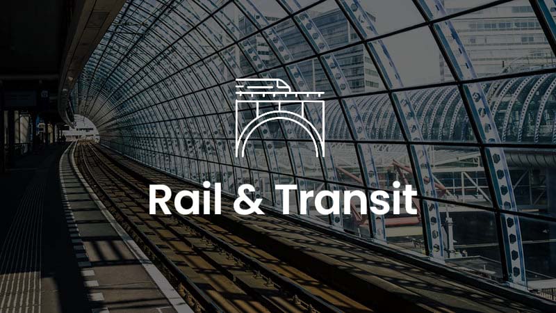 A train station platform with tracks leading into a glass-arched terminal. The text "Rail & Transit" is displayed with a bridge icon above it.