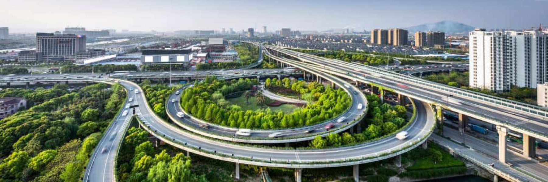 Elevated highways with multiple lanes and interchanges, surrounded by urban buildings and green spaces. Traffic is visible on the roads, a testament to effective roadway design managed by state and local authorities using OpenRoads Designer.