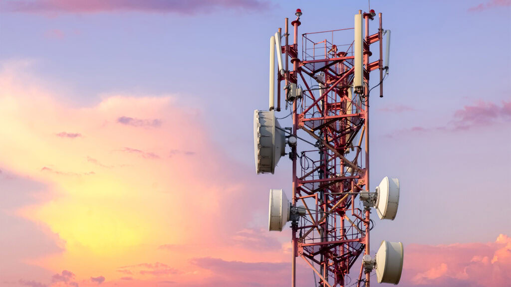 OpenTower stands tall, adorned with antennas and satellite dishes, silhouetted against a vibrant sunset sky.