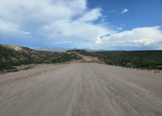 A wide, unpaved dirt road stretches into the distance, flanked by low hills and sparse vegetation under a partly cloudy sky—a scene perfect for this month’s Budgeto Partner Spotlight.